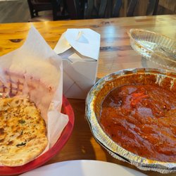 Butter chicken with a side of rice and garlic naan.