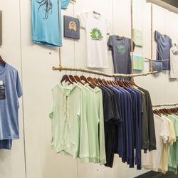 Cinder and Salt - Handmade suspended birch branch clothing racks holding some of our unisex t's and zip hoodies