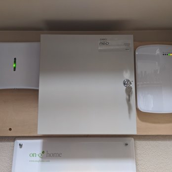 Central Security - The Control Box, Alarm.com Communicator and Wireless Host mounted on the wall in a closet. - Security Systems Near Me - Austin, Texas
