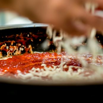 Pizza Now - a person sprinkling cheese on a pizza - Pizza Near Me - West Chicago, Illinois Pizza Now - a person sprinkling cheese on a pizza - Pizza Near Me - West Chicago, Illinois