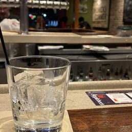 Empty while bartender sits in the corner on her phone with her coworker Empty while bartender sits in the corner on her phone with her coworker