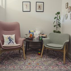 Wolff Osteopathic Medicine - Two chairs pink and pale green with a colorful accent pillow on a colorful rug a physician's waiting room