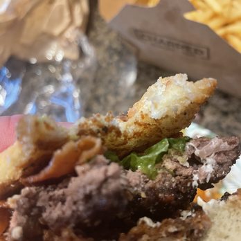 Charred Burger + Bar - a hand holding a half eaten sandwich - Burgers Near Me - Lincoln, Nebraska