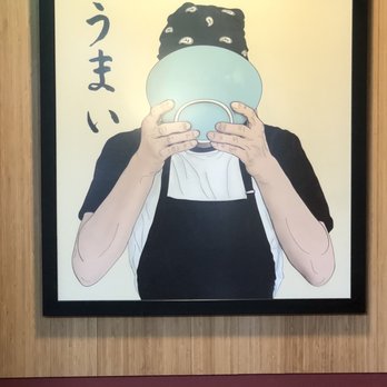 Toshi's Ramen - A framed cartoon illustration depicts a person with a bandana holding a bowl in front of their face, with Japanese characters beside them. - Ramen Near Me - Eugene, Oregon