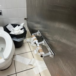 a bathroom with toilet paper on the floor