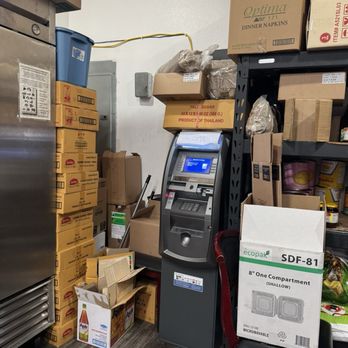 Thai Original BBQ - A bank ATM is placed in a storage area with stacked boxes, shelves, and miscellaneous items around it. - Thai Near Me - Pacifica, California