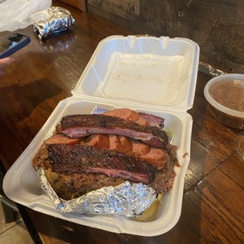 Triple J's Smokehouse - Loaded Potato with an extra rib, sausage, brisket, sour cream and cheese with a side of baked beans - Barbeque Near Me - Houston, Texas