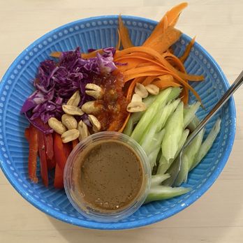 Three Ladies Cafe - Thai  Rainbow Salad Vegan - A vegan rainbow salad with shredded purple cabbage, carrots, celery, red bell peppers, and a small container of dressing, topped with cashews and sauce. - Juice Bars & Smoothies Near Me - Davis, California