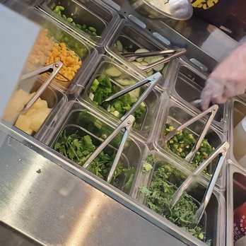 Poke Bar - a person preparing food in a buffet - Poke Near Me - Duluth, Georgia Poke Bar - a person preparing food in a buffet - Poke Near Me - Duluth, Georgia