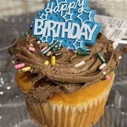 White cupcake with chocolate whipped cream and sprinkles. White cupcake with chocolate whipped cream and sprinkles.