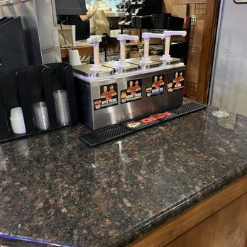 J’s Bbq - The sauce bar. 4 to choose from including vinegar based which I prefer over the sweet. - A stainless steel sauce dispenser with four pumps and labels for different barbecue sauces at a restaurant counter. - Barbeque Near Me - Olathe, Kansas