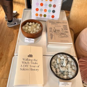 HausWitch - Table features books on Salem history and herbal homesteading, mineral stones in bowls, and a color chart of Salem-themed colors. - Spiritual Shop Near Me - Salem, Massachusetts