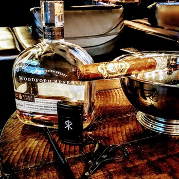 Industrial Cigar - a bottle of whiskey and a bowl on a wooden table - Tobacco Shops Near Me - Frisco, Texas