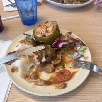 Kettle Restaurant - A plate contains a stuffed jalapeño pepper, mashed potatoes with gravy, and a side salad with tomatoes, onions, and cucumbers. A blue glass with a lemon wedge is nearby. - Breakfast & Brunch Near Me - Tucson, Arizona