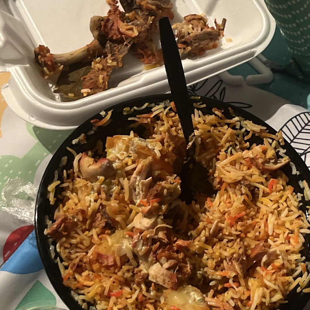 Chicken Biryani in the white container all the bones and top middle the chicken. Rest is rice and potatoes.