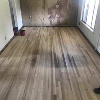 Restore Your Floor Hardwood Flooring - Living room after the wood was stripped back. Note the large dark stain in the middle of the room. - Flooring Near Me Restore Your Floor Hardwood Flooring - Living room after the wood was stripped back. Note the large dark stain in the middle of the room. - Flooring Near Me