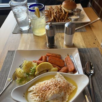 NaCl + H2O - NOT the beloved mahi. This is their cod. - A table setting with a plate of mashed potatoes, carrots, and a creamy dish, alongside a burger with fries and drinks in the background. - Cocktail Bars Near Me - Rolla, Missouri