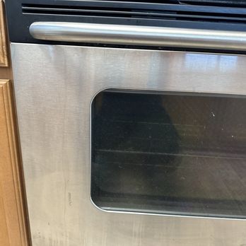 Super Maids - None of the stainless steel appliances was wiped down or cleaned - A stainless steel oven with a glass door is installed in a kitchen with wooden cabinets on the side. - Home Cleaning Near Me