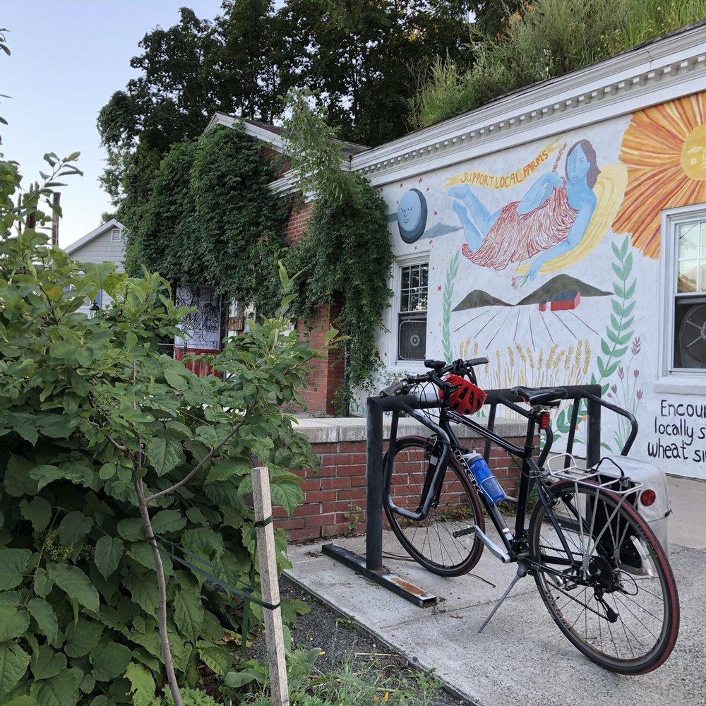 Hungry Ghost Bread - Outside. Out front patio, bike rack, and seating amongst the plants. - Bakeries Near Me - Northampton, Massachusetts Hungry Ghost Bread - Outside. Out front patio, bike rack, and seating amongst the plants. - Bakeries Near Me - Northampton, Massachusetts