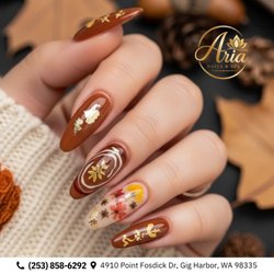 Aria Nails & Spa - Pressed autumn florals! Almond extensions showcase rich caramel tones, gold leaf flake accents, and delicate encapsulated blooms. Book!