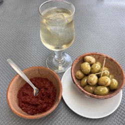 Elyssa - 5/7/26 FYI. Such a small glass of wine + two large ice cubes?!?! Complimentary hot sauce and olives.