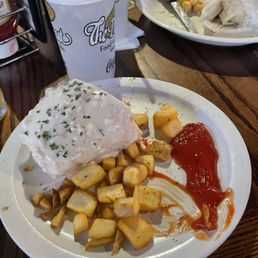 Half of a breakfast burrito and a side of potatoes. Half of a breakfast burrito and a side of potatoes.