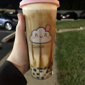 CloudTea - Signature brown sugar latte w/ boba and 2 shots espresso, "milk cloud" added - A person holds a bubble tea with a pink lid and a cute cloud logo, with tapioca pearls at the bottom, outside at night. - Bubble Tea Near Me - Roselle, Illinois
