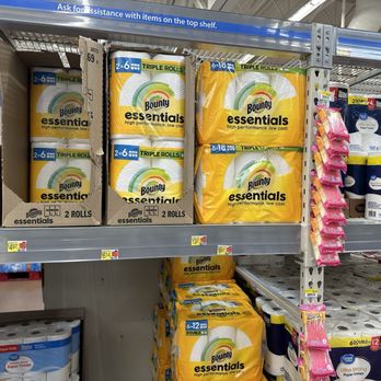 Walmart Supercenter - Store shelves at Walmart Supercenter in Dixon, Illinois, are stocked with Bounty Essentials paper towels in different pack sizes, including 2-roll and 6-roll packages. The packaging features a yellow and white design with a rainbow logo. Price tags are visible below the products, and pink hanging tags are attached to the side of the shelf. The image shows a typical retail display of paper towels in a grocery or big-box store setting. - Grocery Near Me - Dixon, Illinois