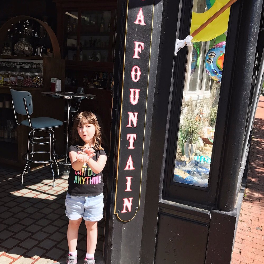 a little girl standing in front of a store