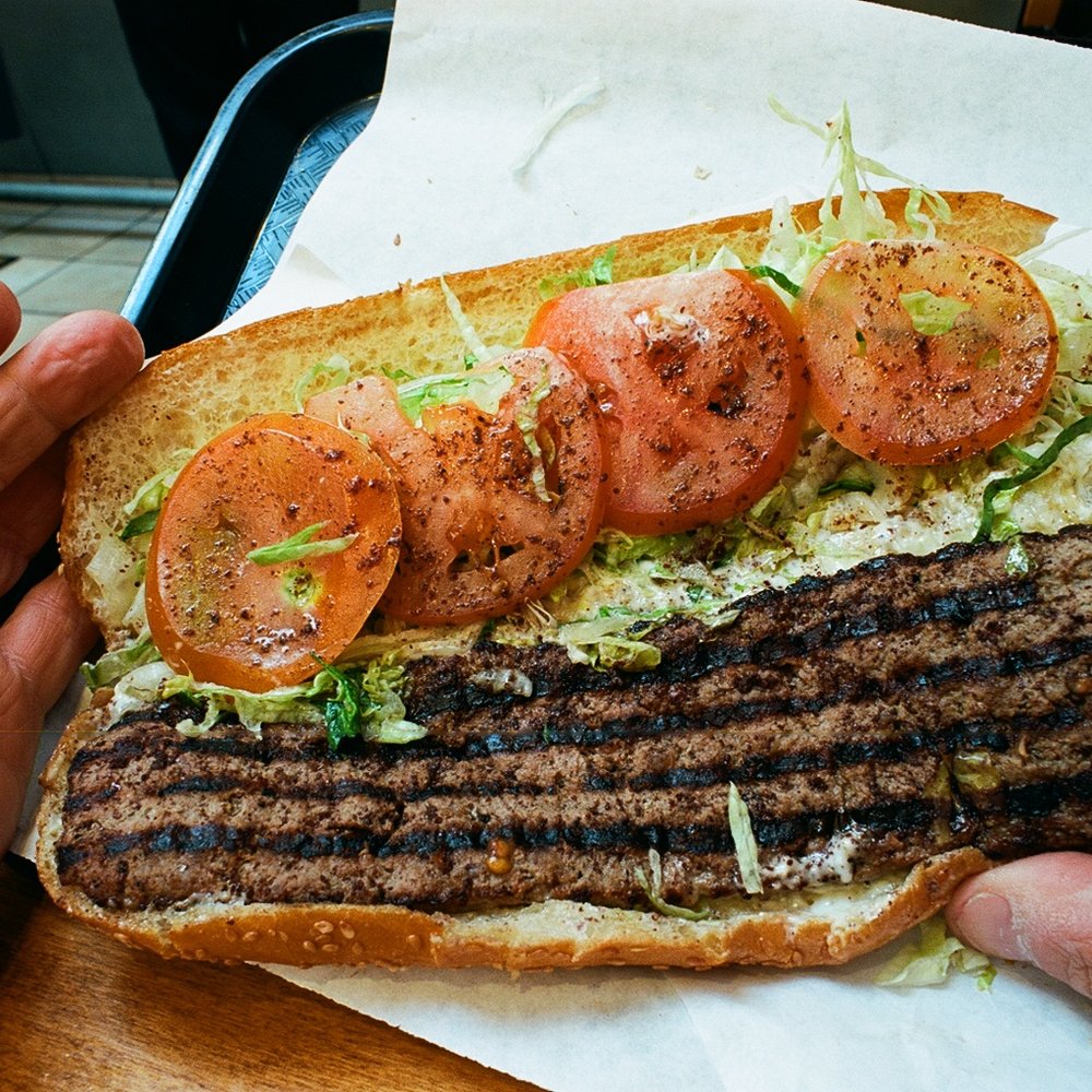Bongo Burger - Close-up photo of the Persian burger, showing stripes made by grill, and somagh berries sprinkled on top. - Burgers Near Me - Berkeley, California