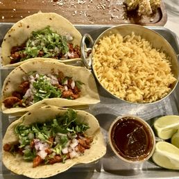 Tacos Al Pastor with hot sauce limes and rice