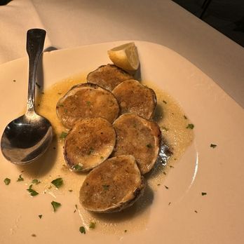 Bella Napoli - Clams Oreganata - A plate of Clams Oreganata garnished with chopped herbs, lemon wedge, and served with a sauce, on a white dish. - Italian Near Me - Bloomfield, New Jersey