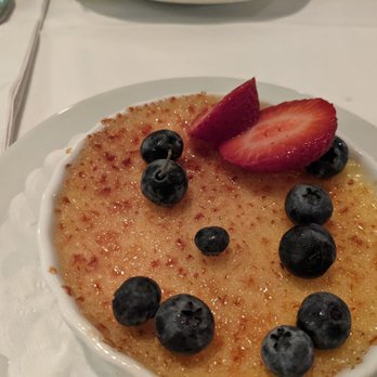 Surfside - Creme brulee ! Delicious! - A crème brûlée dessert garnished with blueberries and a sliced strawberry, served on a white plate at a restaurant. - Seafood Near Me - Montauk, New York