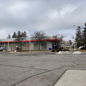 Petro-Canada - Petro-Canada & Car Wash - car wash - A mostly empty parking lot in Concord, ON, with a Petro-Canada gas station and car wash building in the background, under cloudy skies. - Gas Stations Near Me - Concord, Ontario