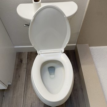 Simply Clean - After cleaning - A white toilet with an open lid is positioned against a wall, with a toilet paper roll on top of the tank in a bathroom setting. - Home Cleaning Near Me - bellflower, California