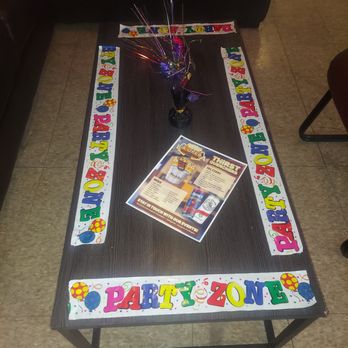 La Opera - A rectangular table features a colorful "Party Zone" border decoration, a small balloon bouquet in a black vase, and a menu flyer in the center, set in an indoor space. - Bars Near Me - Waukegan, Illinois