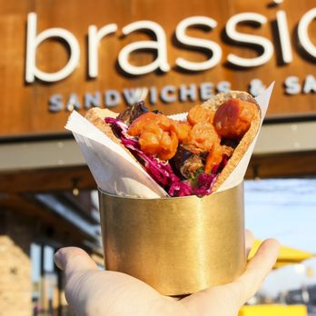 Brassica - a person holding a sandwich in front of a sandwich shop - Salad Near Me - Westlake, Ohio Brassica - a person holding a sandwich in front of a sandwich shop - Salad Near Me - Westlake, Ohio