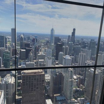John Hancock Center - City view - A panoramic view of Chicago's downtown skyline seen through a window with a grid pattern, showcasing numerous skyscrapers and Lake Michigan in the distance. - Landmarks & Historical Buildings Near Me - Chicago, Illinois