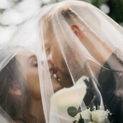 Reedsburg Country Club - Bride and groom kissing under the vail