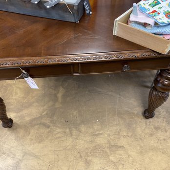 3 Vintage Chicks - Solid wood desk. Can't find these in the stores anymore - A dark wood vintage desk featuring carved decorative edges and a single drawer with a metal handle, situated on a concrete floor. - Furniture Stores Near Me - Phoenix, Arizona