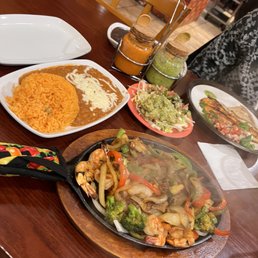 Shrimp fajitas with onions, peppers, broccoli and squash, yellow rice, and pinto beans the way they should be and guacamole