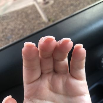 Wendy's Nails - Awful job. - The image depicts a hand with fingers extended, showing nails that are chipped or broken. The hand is inside a vehicle, with the car's interior visible, including a black dashboard and a side mirror. Outside the vehicle, a gravel area and some structures are visible, but they are out of focus. - Nail Salons Near Me - Phoenix, Arizona