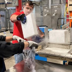 A+ Heler's Dry Ice - Employee's at A+ Heler's Dry Ice packaging a 10x10x2 (10 lb.) dry ice slab cut from a 50 lb. block for a customer.