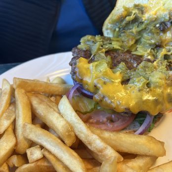 Gabby's Diner - Burger with green chilis - A cheeseburger topped with green chilies, tomato, and onions, served with a side of French fries on a white plate. - American Near Me - Milan, New Mexico