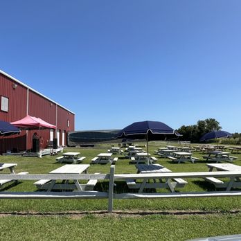 Sanctuary Vineyards - picnic tables and umbrellas in front of a red barn - Wineries Near Me - Jarvisburg, North Carolina Sanctuary Vineyards - picnic tables and umbrellas in front of a red barn - Wineries Near Me - Jarvisburg, North Carolina