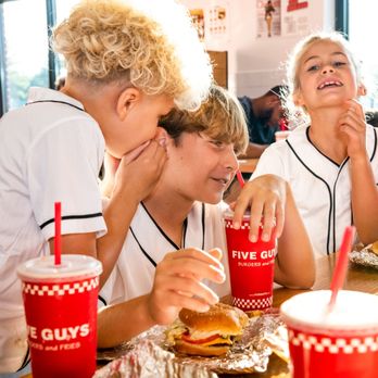 Five Guys - Children chat and laugh while enjoying their Five Guys meals at a dining room table in a Five Guys restaurant. - Burgers Near Me - Lubbock, Texas Five Guys - Children chat and laugh while enjoying their Five Guys meals at a dining room table in a Five Guys restaurant. - Burgers Near Me - Lubbock, Texas
