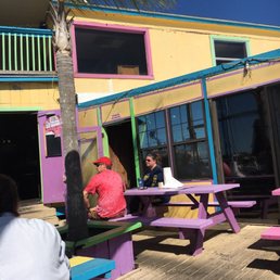 people sitting at picnic tables in front of a colorful building people sitting at picnic tables in front of a colorful building