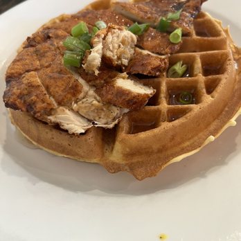 Tank and Libby's - Chicken & Waffle - A waffle topped with cooked chicken pieces and garnished with chopped green onions, served on a white plate. - Breakfast & Brunch Near Me - Drexel Hill, Pennsylvania