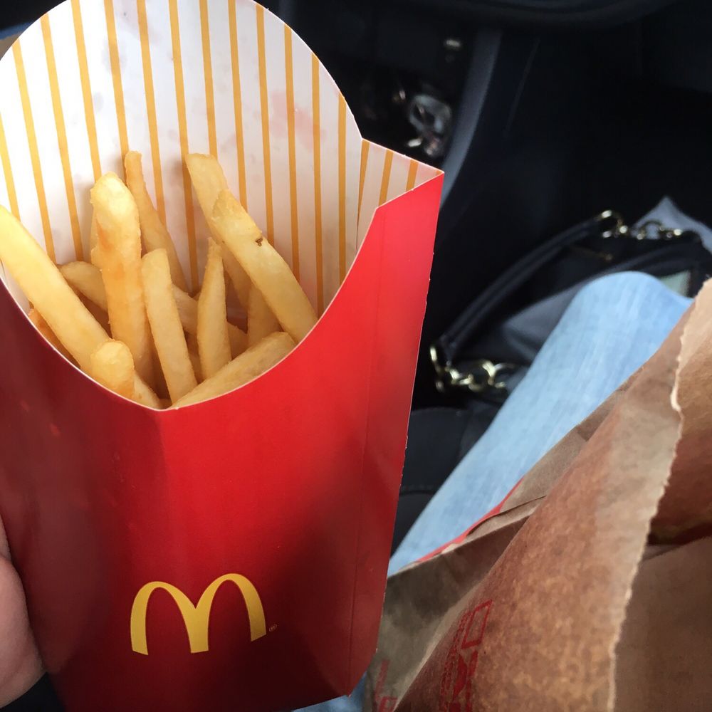 a person holding a bag of french fries a person holding a bag of french fries