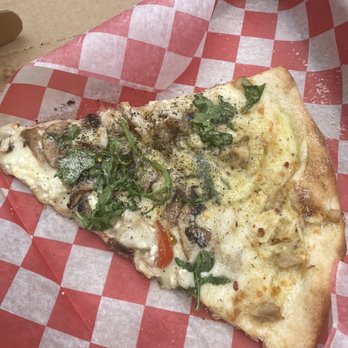 Wiseguy Pizza - Chicken Parmesan Pie - A single slice of pizza with a thin crust, topped with melted cheese, sliced mushrooms, and chopped green herbs, placed on red and white checkered paper inside a cardboard box. - Pizza Near Me - Washington, DC, District of Columbia